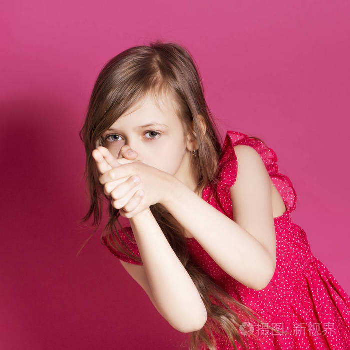 8岁的小女孩在粉红色的中性背景下用手做一些情绪化的手势她有长黑发