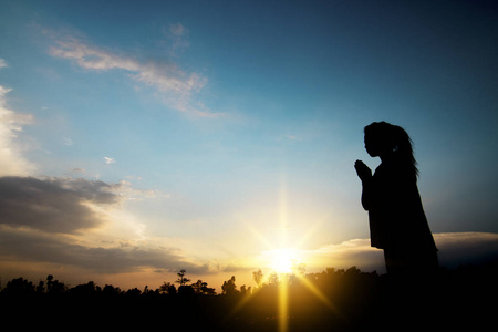 祈祷和希望的概念, 妇女的剪影为桃祈祷和成功在日落的生活中