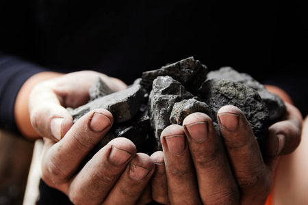 煤矿矿工在人手中的煤炭背景。煤炭开采或能源环保。工业煤。火山岩
