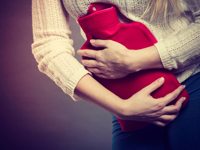 女人有感觉很不舒服,抱着热水袋的胃痉挛照片