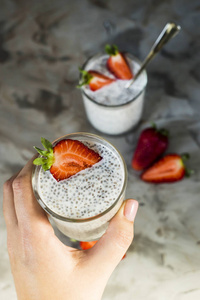 一个女人的手拿着一份来自嘉和牛奶和草莓的布丁.