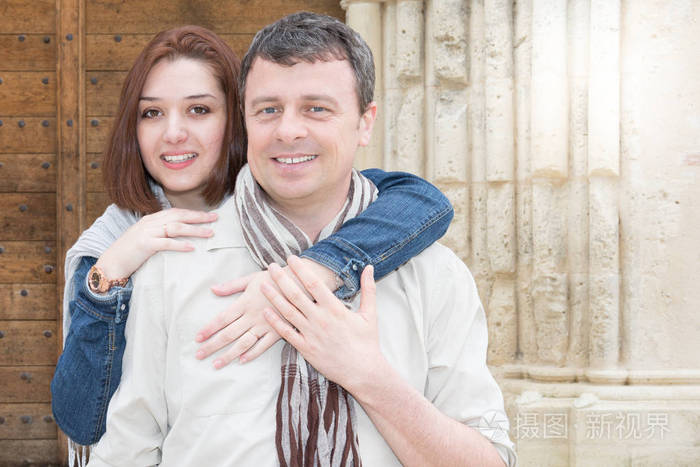 旅游夫妇与美丽的女人英俊的男人有乐趣快乐的女孩拥抱男人背后的古老