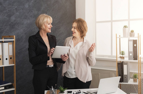 两位商界女性同事在平板电脑上合作