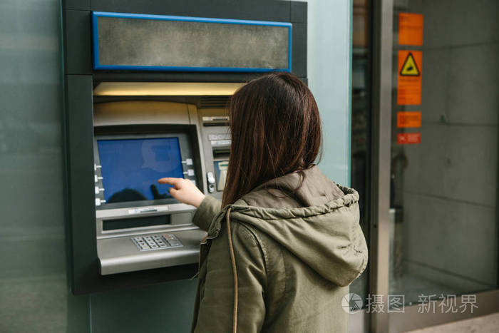 一个年轻女人从atm机里拿钱从atm机上取一张卡金融信用卡取款