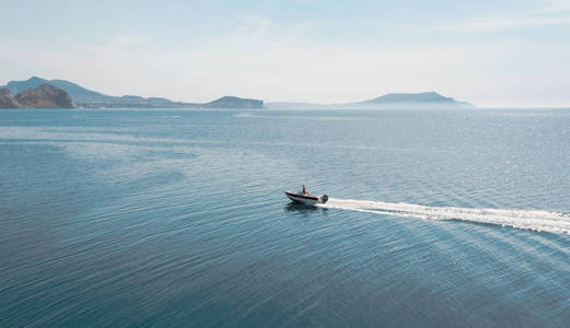 海景与地平线上的山脉和漂浮在水面上的机动船。克里米亚