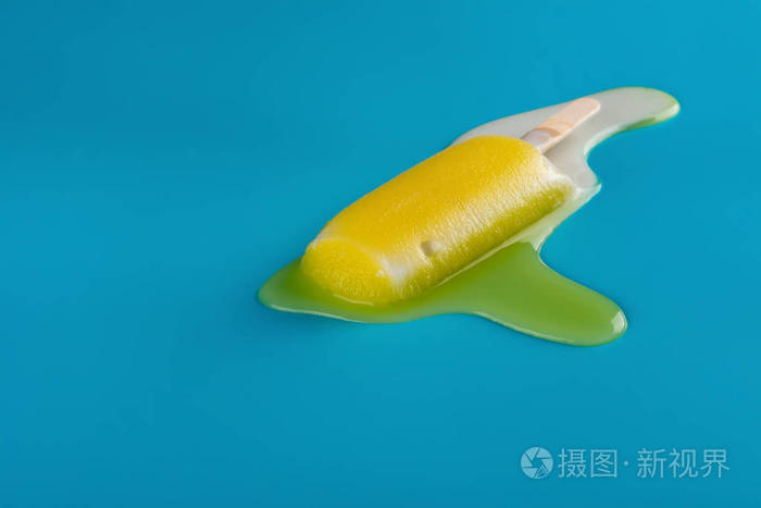 蓝色背景下的熔化过程中的侧面视图黄色冰棒