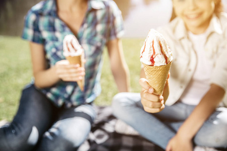 一张美味的冰淇淋图片。图片上有两个缺点。女孩们拿着它。小的人在微笑