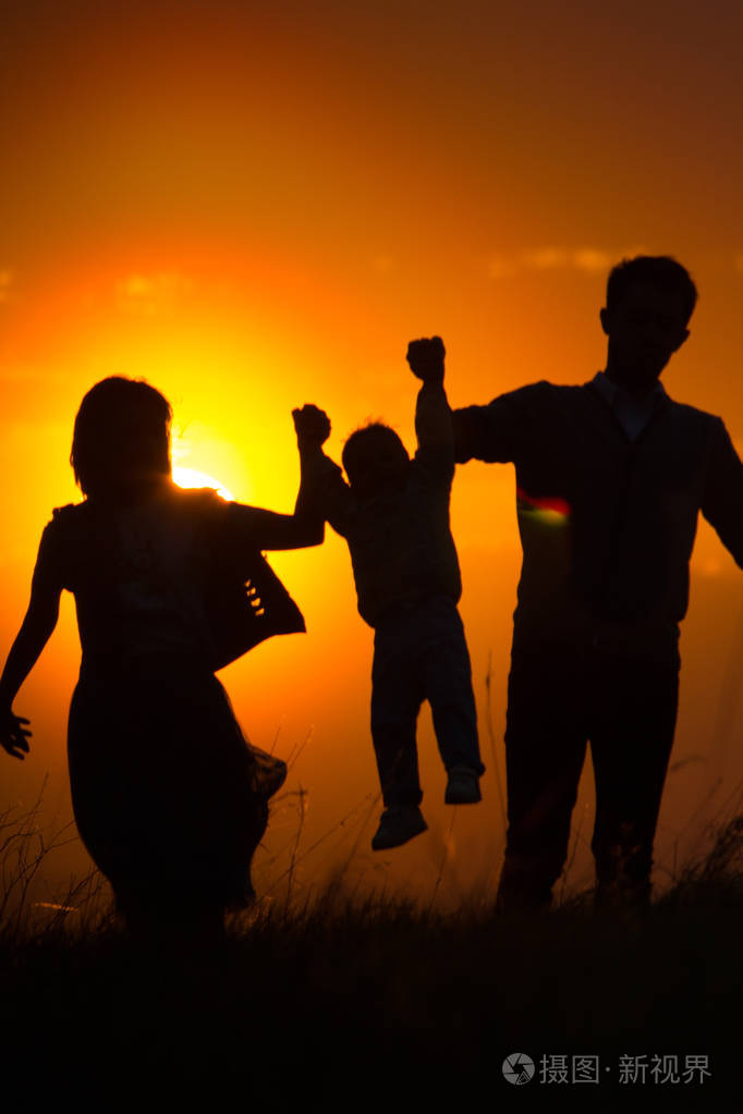 照片 一家人走过田野欣赏夕阳, 爸爸和妈妈牵着手, 儿子坐在他的肩膀