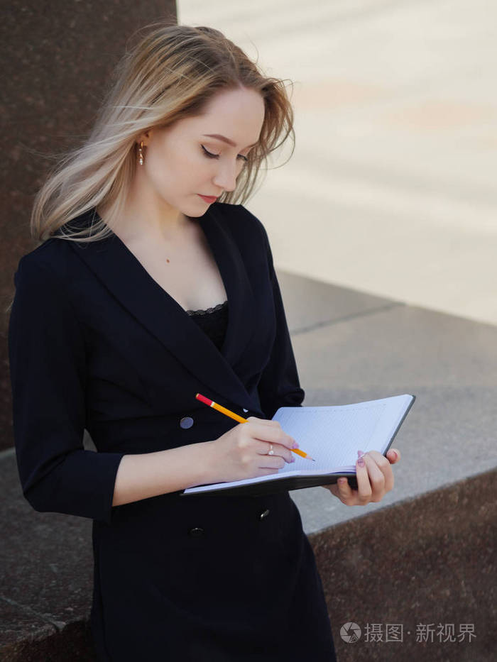 用铅笔在笔记本上写字的女人