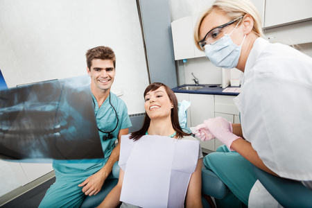 牙医与女助理显示 x 射线图像的病人