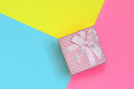 粉红色的小礼品盒躺在纹理背景的时尚粉彩蓝色, 黄色和粉红色的颜色纸在最小的概念