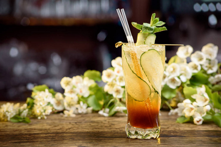 夏季鸡尾酒与黄瓜在一个木桌上的花卉背景