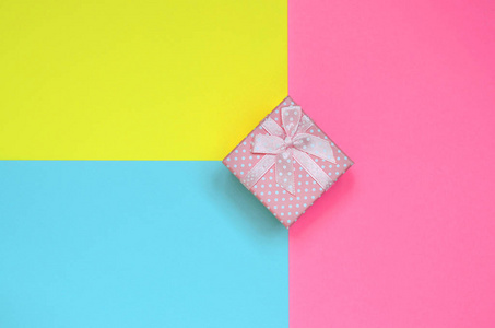 粉红色的小礼品盒躺在纹理背景的时尚粉彩蓝色, 黄色和粉红色的颜色纸在最小的概念