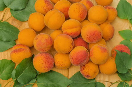 杏在木头上。成熟的杏在木质背景。木桌特写上有叶子的有机杏