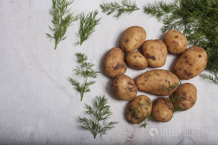 白色的木制背景上的新鲜原料土豆。顶视图