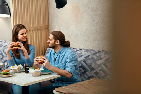 情侣汉堡。男人和女人在咖啡馆里吃快餐。高分辨率