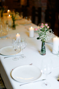 白色桌上的花白盘子和蜡烛的 Bouguet