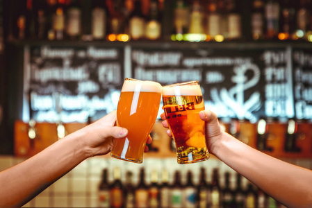 两个朋友在酒吧里用一杯淡啤酒举杯祝酒。美丽的啤酒节的背景。细粒