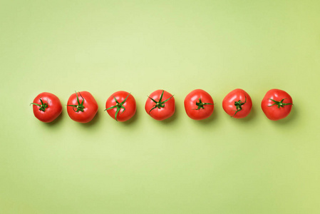 在绿色的背景下排上新鲜的红色西红柿。顶部视图。复制空间。最小的设计。素食素食有机食品和碱性膳食概念