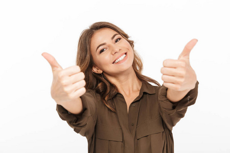 一个快乐的年轻女子的肖像显示竖起大拇指在白色背景孤立照片
