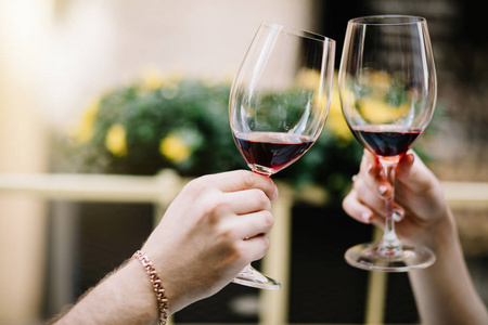 干杯.一对年轻的情侣坐在一起, 微笑着, 举杯与两个红酒酒杯照片