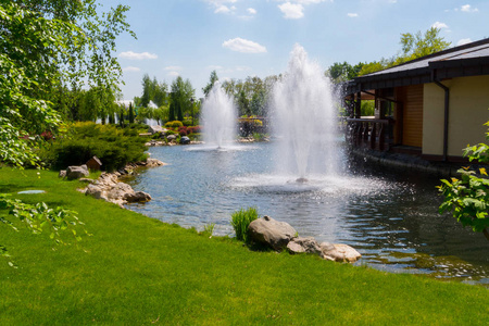 绿色的喷泉清新透明的喷泉, 在池塘中间的蓝色天空与一侧的绿色草坪和