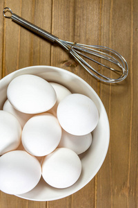 一组鸡蛋在一个深白色的碗旁边的一个搅拌等待厨师使用他们在一顿饭