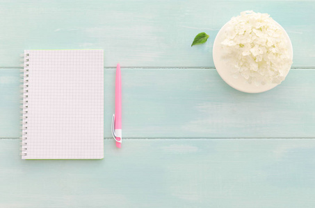 打开笔记本与粉色的笔 咖啡杯和薄荷木制背景上的绣球。头顶上的副本空间背景，平坦的顶视图