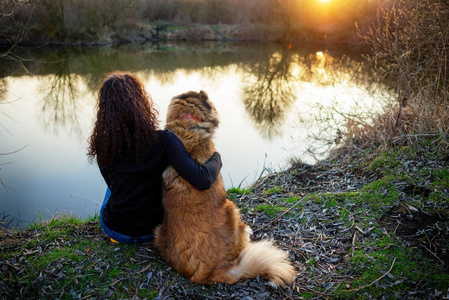 年轻女子在一个令人愉快的春日玩高加索牧羊犬