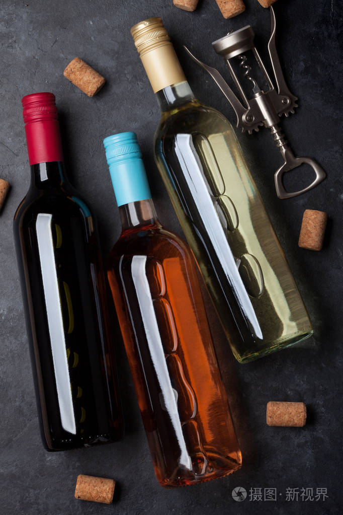 黑色石桌上的红色,粉红色和白色葡萄酒瓶.顶部视图