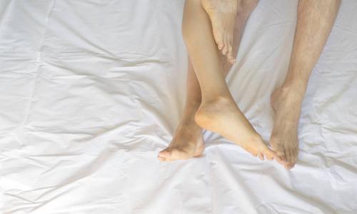 情侣头枕在床羽绒被的脚