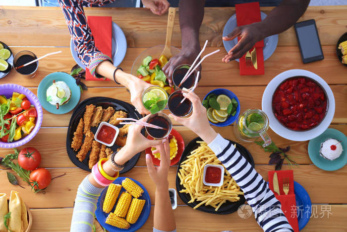 顶视图的一群人在一起时坐在木桌吃饭.在桌子上的食物.人们吃快餐
