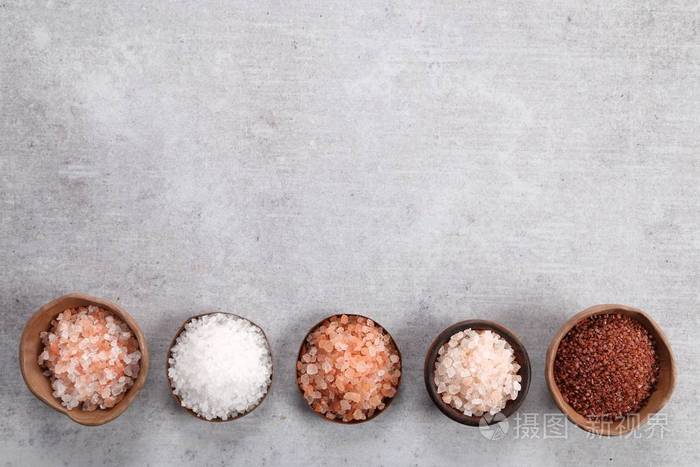 各种类型的表盐在碗中的灰色背景顶部视图