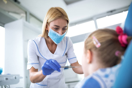 年轻的女牙医正在检查一个小女孩的牙齿