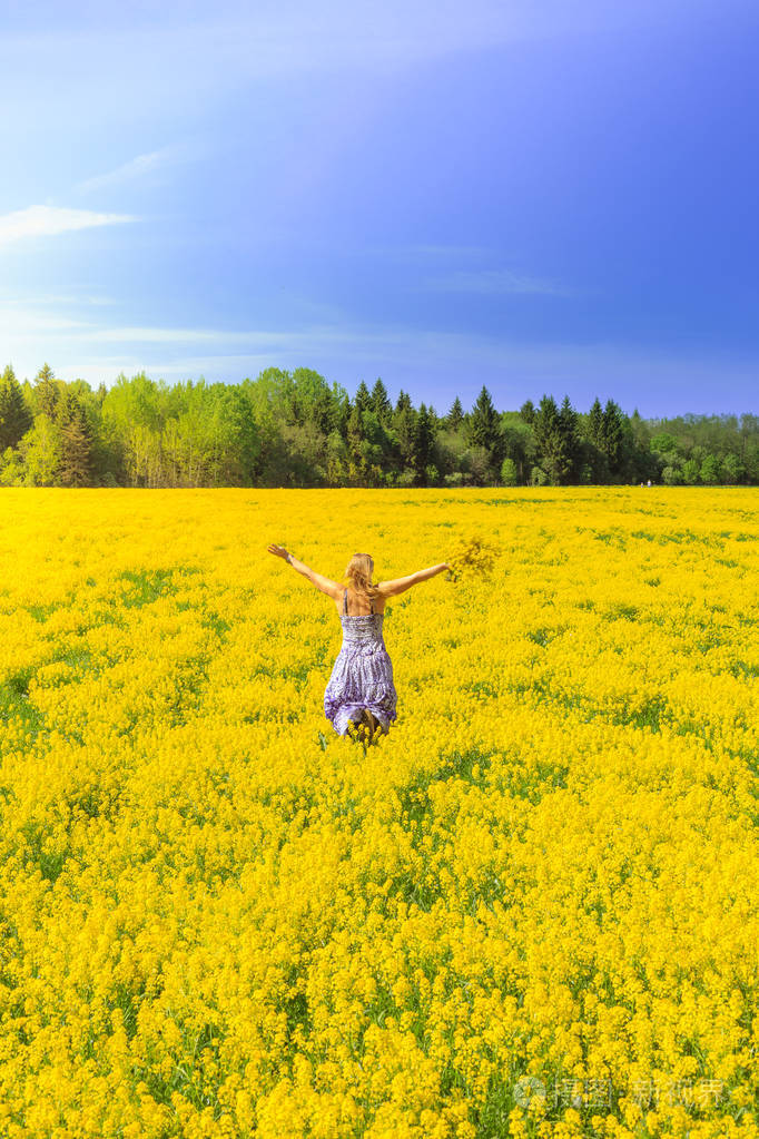 快乐的女孩奔跑横跨黄色领域与花束花