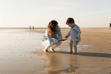 年轻母亲探索海滩与幼儿图片