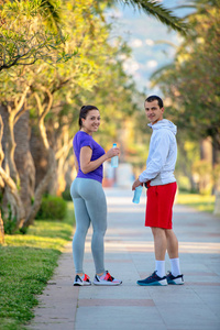 年轻运动的人和妇女在运动装饮用水在慢跑以后