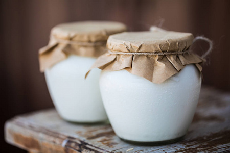 新鲜自制酸奶在罐子里。早餐用白牛奶天然生物产品