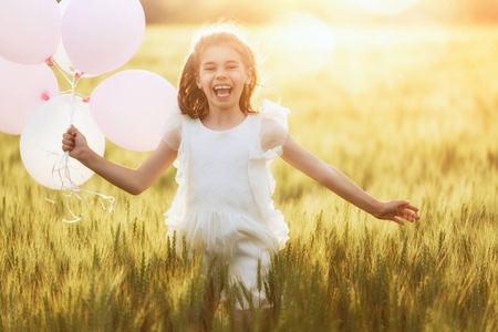 快乐的孩子在夏天玩大自然。在日落的背景下, 孩子在草地上笑着玩耍。气球的女孩正在谷物场上奔跑