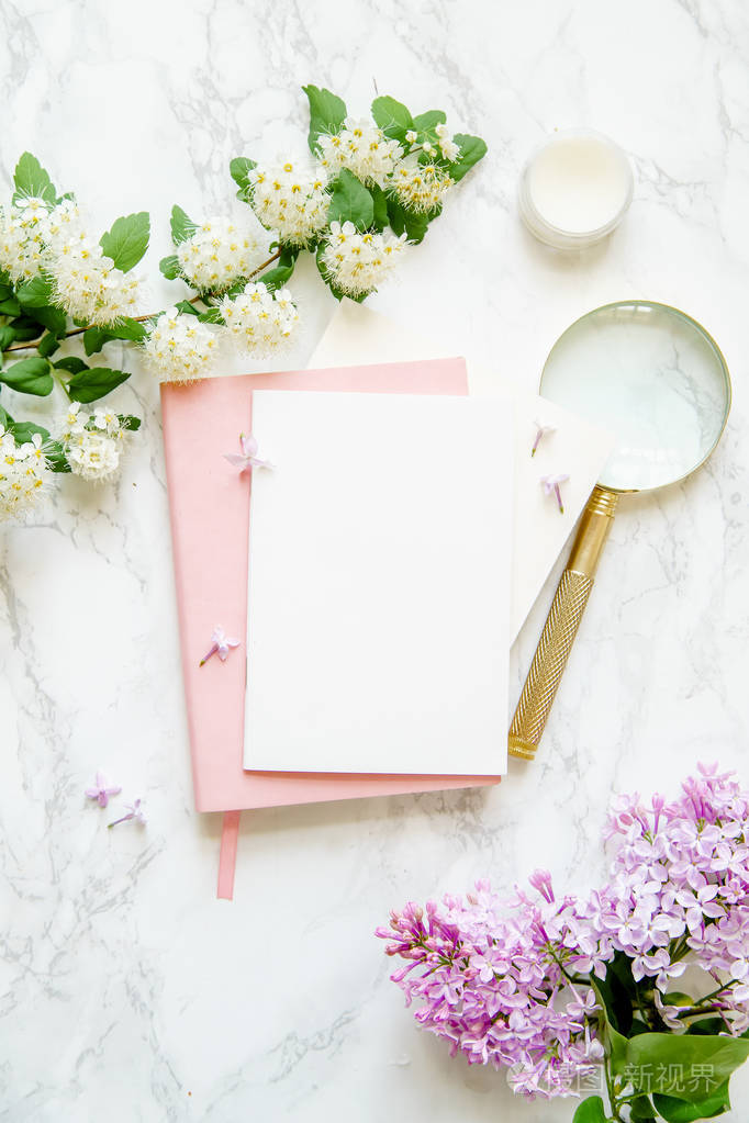 粉红色笔记本和奶油与白色和丁香花金色放大镜大理石背景, 女性博客工作空间的概念