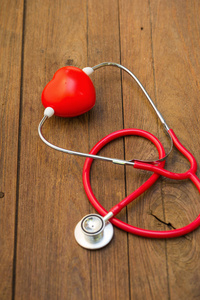 听诊器用木制背景上的红色心