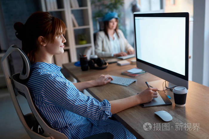 设计师团队精神-微笑的妇女工作到深夜在办公室电脑