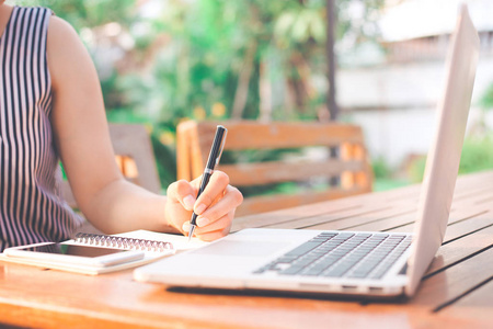 商业妇女写在记事本与一支钢笔在花园里在法郎