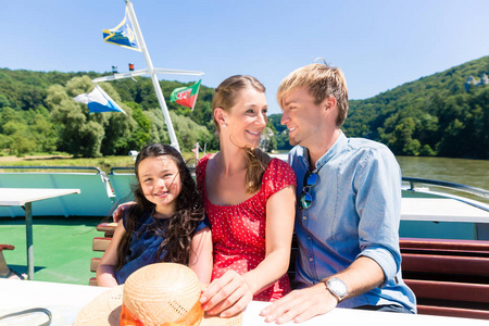 快乐的家庭坐在小船上在河巡航在夏天