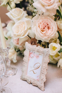 插花的白色玫瑰和一个美丽的框架与数字二, 在宴会上的餐桌编号。垂直