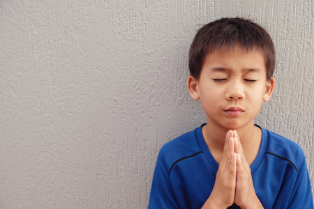 亚洲男孩闭着眼睛祈祷照片