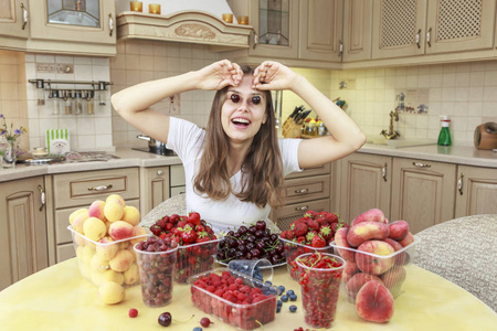 美丽的年轻女孩吃水果和新鲜的浆果在厨房里, 眼睛覆盖着樱桃