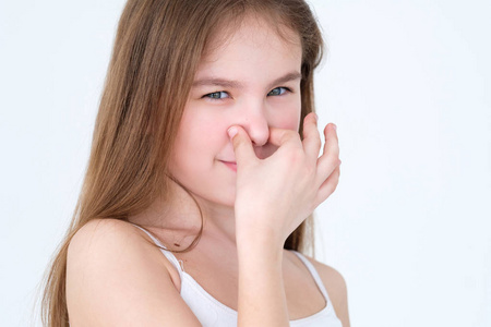 臭味.孩子遮住了鼻子.白色背景的小女孩肖像.面部表情概念照片