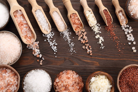 各种类型的盐在木勺和碗中。顶部视图