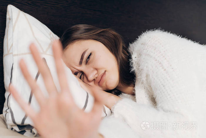 不满的年轻女孩在白色睡衣醒来一大早不想起床